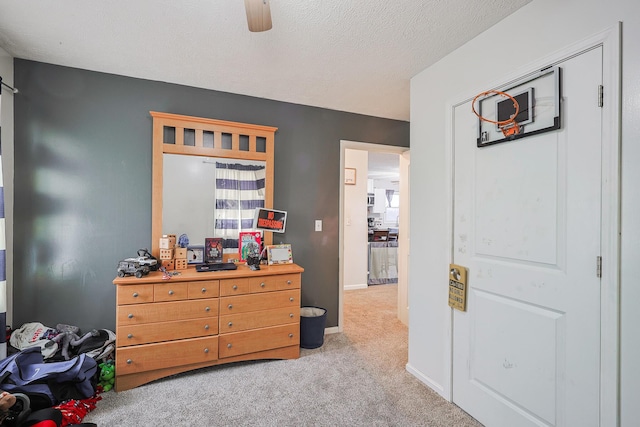 bedroom featuring ceiling fan, light carpet, and a textured ceiling