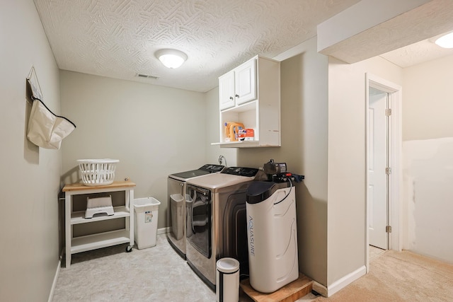 laundry area with washing machine and dryer, cabinets, and a textured ceiling