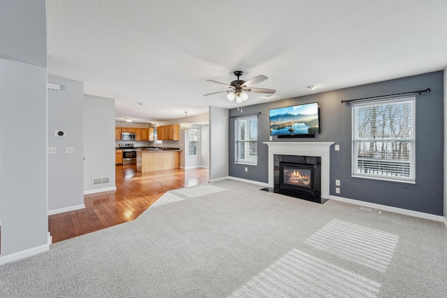 living room with ceiling fan, light colored carpet, plenty of natural light, and a tile fireplace