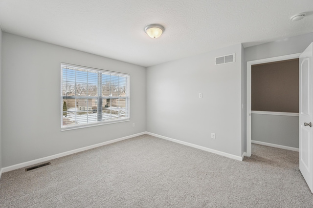 carpeted empty room featuring a textured ceiling