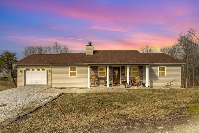 ranch-style home with a porch, an attached garage, a yard, driveway, and a chimney