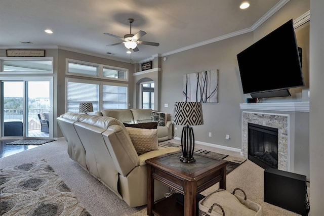 living room featuring crown molding, ceiling fan, a fireplace, and carpet floors