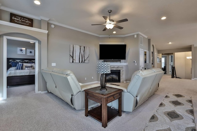 carpeted living room with crown molding, a fireplace, and ceiling fan