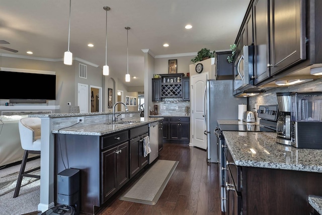 kitchen with hanging light fixtures, a spacious island, sink, and stainless steel appliances