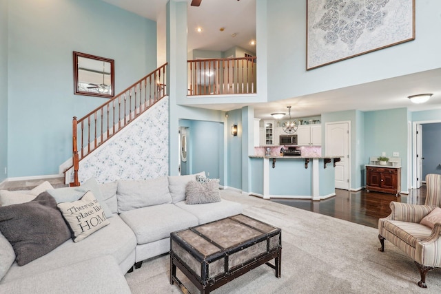 living room featuring a high ceiling, wood-type flooring, and ceiling fan