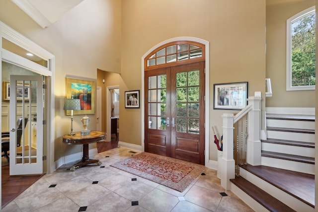 tiled foyer featuring french doors and a towering ceiling