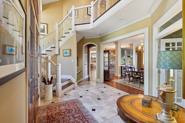 tiled foyer with a high ceiling, crown molding, and decorative columns