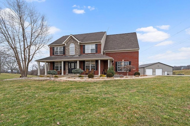 colonial inspired home featuring a garage, an outdoor structure, a front yard, and covered porch