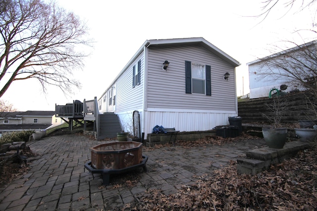 rear view of house with stairs, a fire pit, a deck, and a patio