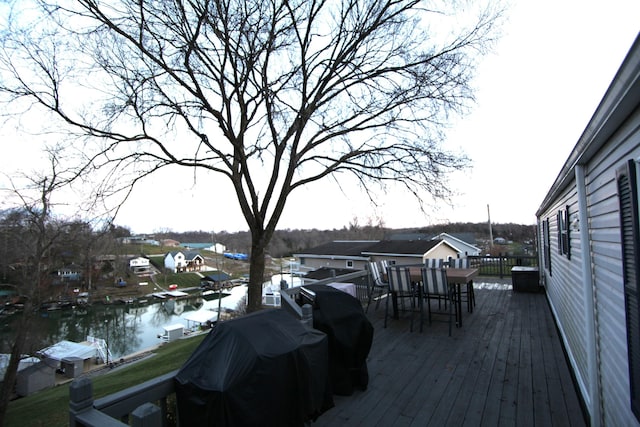 wooden terrace with a residential view, outdoor dining area, and a water view