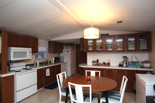 kitchen with light countertops, glass insert cabinets, vaulted ceiling, a sink, and white appliances