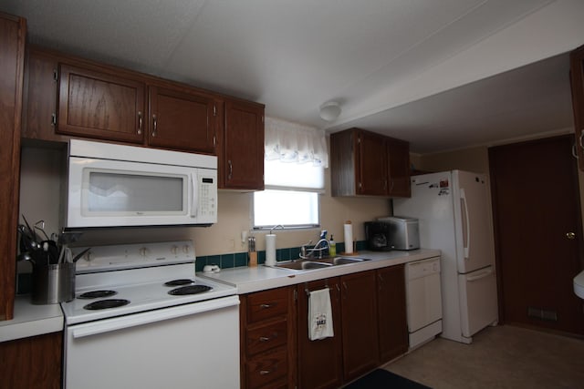 kitchen featuring white appliances, light countertops, and a sink