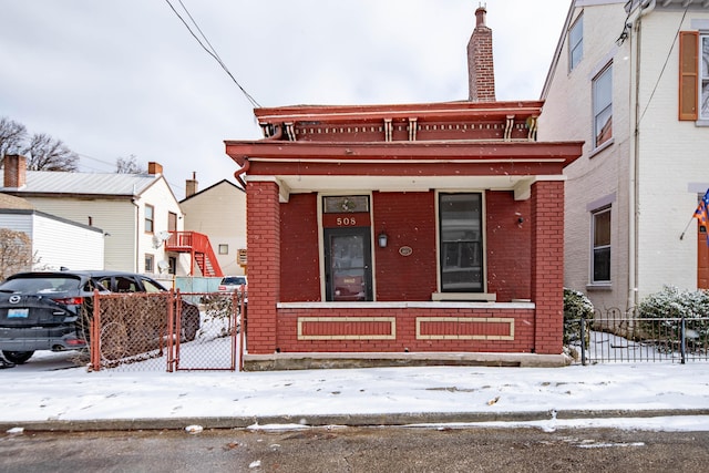 view of front facade featuring a chimney, fence, a porch, and brick siding