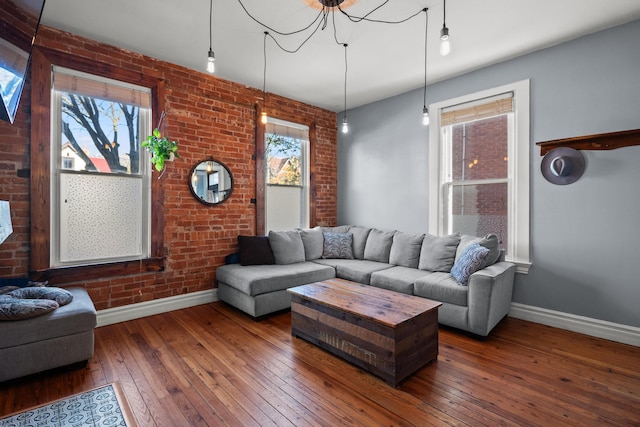 living room with dark hardwood / wood-style flooring and brick wall