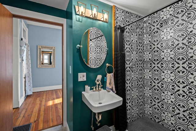 bathroom with wood-type flooring, sink, and curtained shower