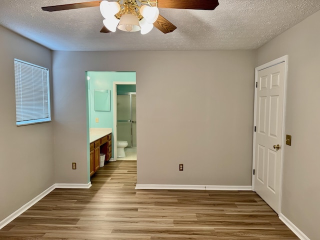 unfurnished bedroom with ceiling fan, a textured ceiling, ensuite bath, and light hardwood / wood-style flooring