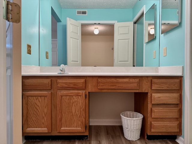 bathroom with vanity, wood-type flooring, and a textured ceiling