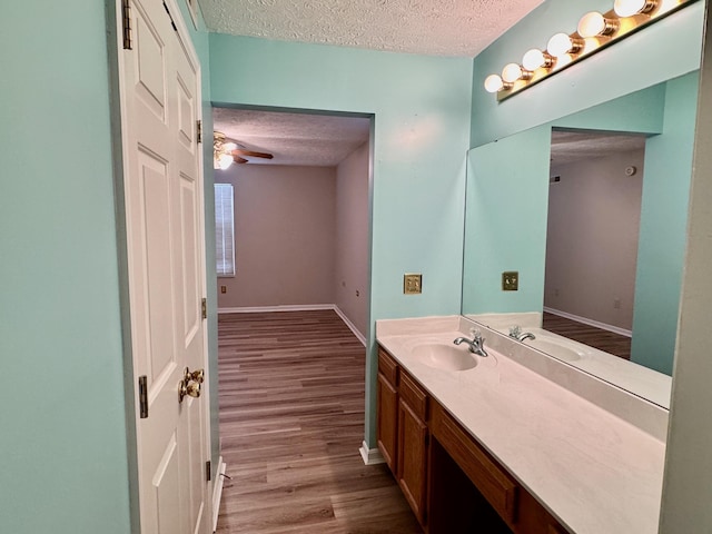 bathroom featuring ceiling fan, vanity, hardwood / wood-style floors, and a textured ceiling