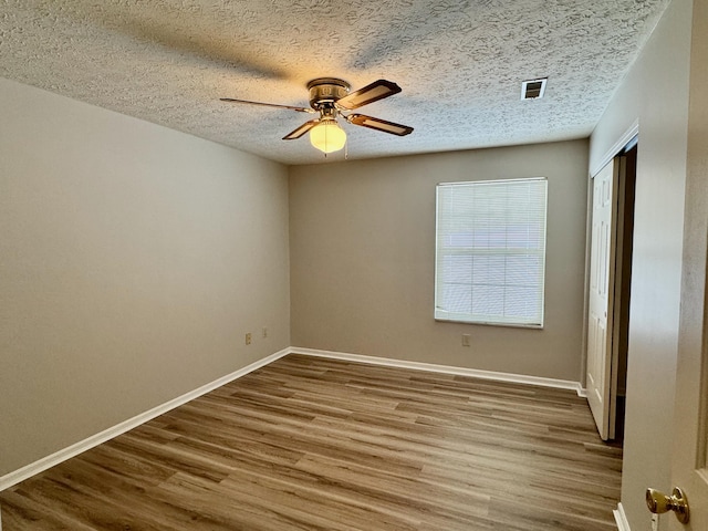 spare room with ceiling fan, wood-type flooring, and a textured ceiling