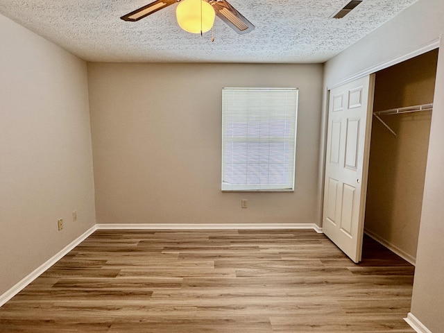 unfurnished bedroom with ceiling fan, light hardwood / wood-style floors, a closet, and a textured ceiling