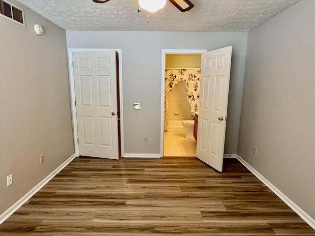 unfurnished bedroom featuring hardwood / wood-style flooring, ceiling fan, connected bathroom, and a textured ceiling