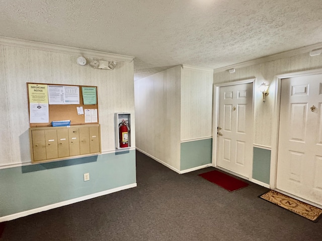 interior space with ornamental molding, mail boxes, a textured ceiling, and dark colored carpet