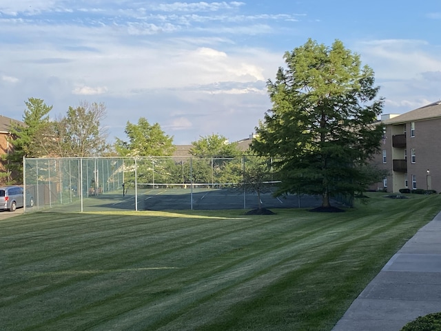 view of property's community featuring a yard and tennis court