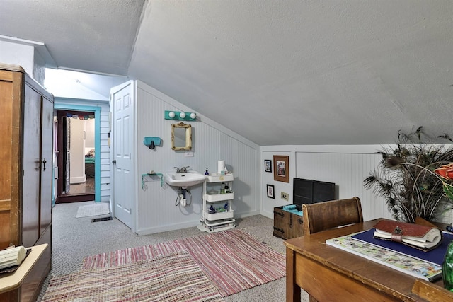 carpeted office with vaulted ceiling and a textured ceiling