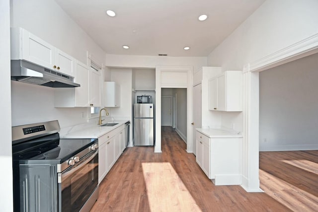 kitchen featuring light wood-type flooring, appliances with stainless steel finishes, sink, and white cabinets