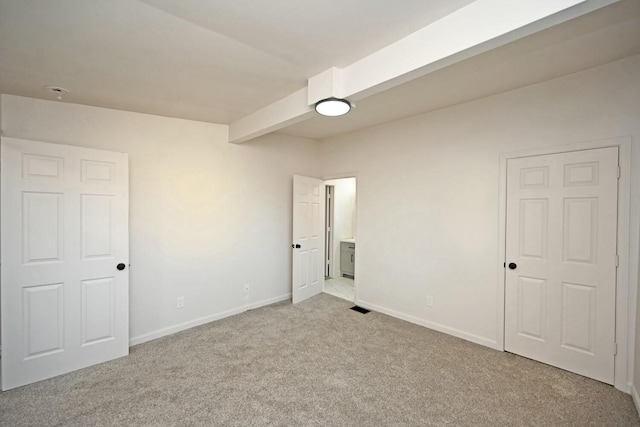 unfurnished bedroom with beamed ceiling and light carpet