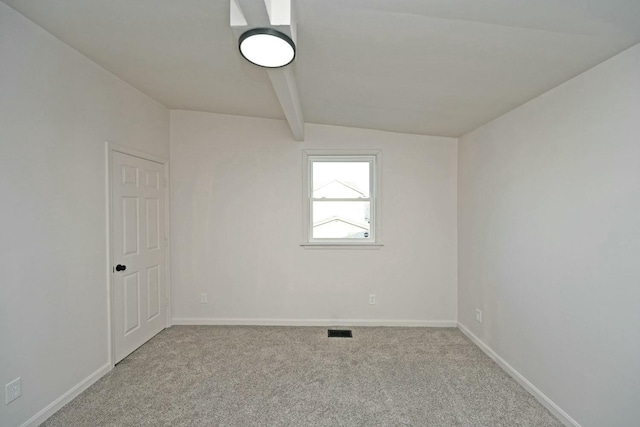 empty room with light carpet and beam ceiling