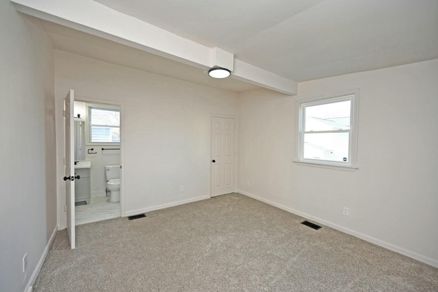 unfurnished bedroom with ensuite bath and carpet floors