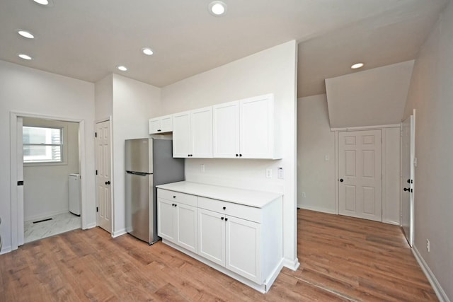 kitchen with washer / clothes dryer, stainless steel fridge, white cabinets, and light wood-type flooring