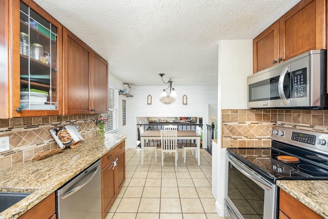 kitchen with stainless steel appliances, brown cabinetry, and glass insert cabinets