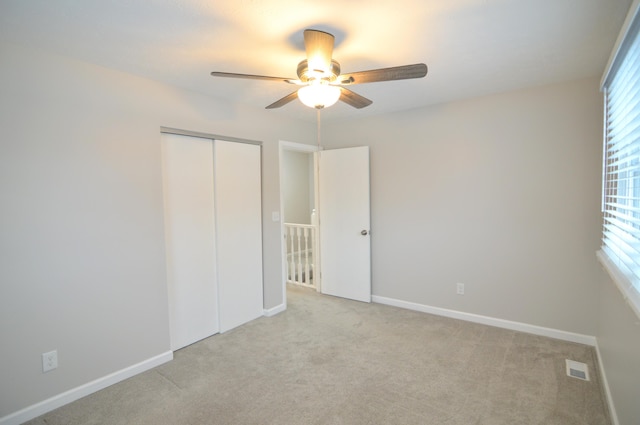 unfurnished bedroom with light colored carpet, a closet, and ceiling fan