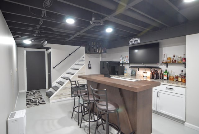 bar with black refrigerator, butcher block countertops, and white cabinets