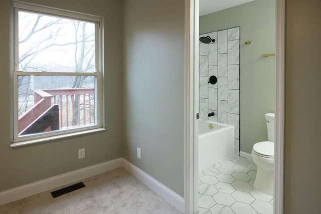 bathroom with tiled shower / bath combo, a wealth of natural light, and toilet