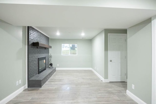 unfurnished living room with a brick fireplace and light wood-type flooring