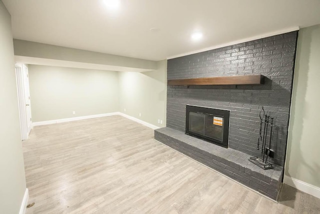 unfurnished living room with a brick fireplace and light hardwood / wood-style flooring