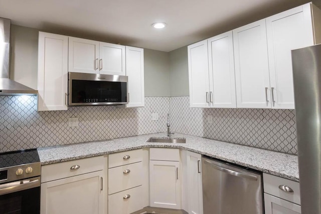 kitchen featuring appliances with stainless steel finishes, sink, white cabinets, and wall chimney exhaust hood