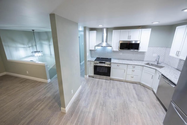 kitchen with white cabinets, appliances with stainless steel finishes, sink, and wall chimney range hood