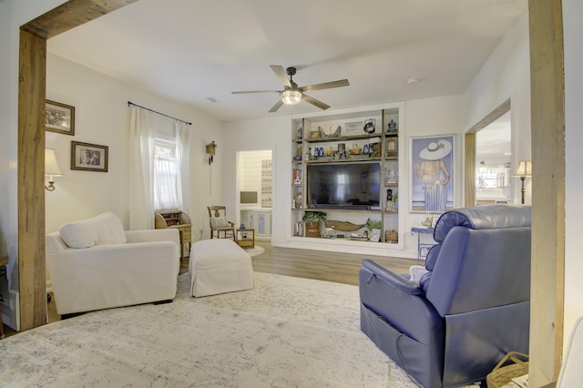 living room featuring wood-type flooring, built in features, and ceiling fan