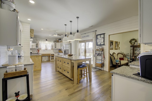 kitchen with decorative light fixtures, a wealth of natural light, a kitchen island, and white cabinets