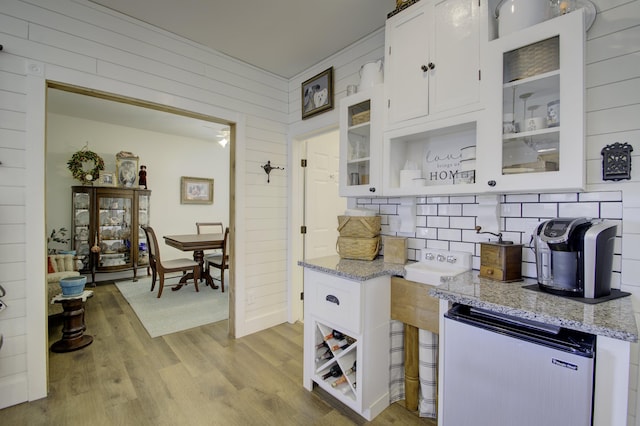 kitchen featuring white cabinetry, stainless steel fridge, light stone countertops, and light wood-type flooring