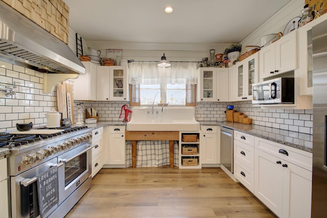 kitchen with stainless steel appliances, extractor fan, light stone countertops, and white cabinetry