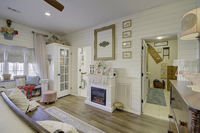 living room with hardwood / wood-style flooring, ceiling fan, and wooden walls