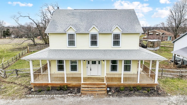 country-style home with fence, a porch, and roof with shingles