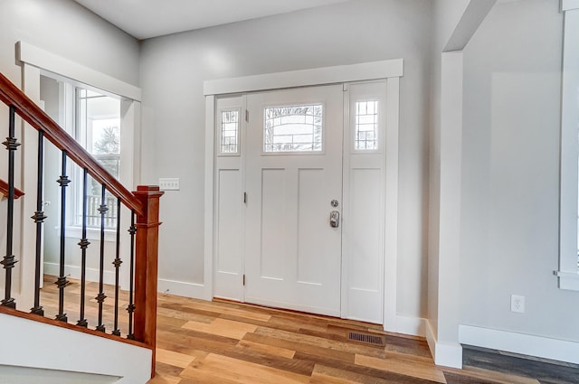 entrance foyer with light wood-style flooring, visible vents, baseboards, and a wealth of natural light