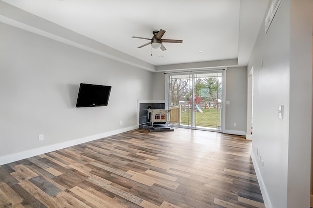 unfurnished living room with a ceiling fan, baseboards, and wood finished floors