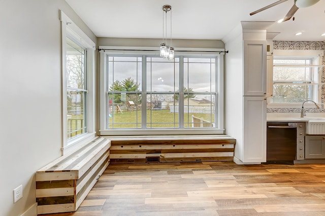 unfurnished dining area with light wood-type flooring, ceiling fan, and a sink